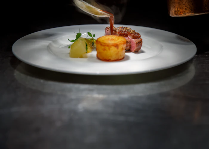 Sauce finished over the plate at the pass